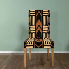 a black and gold patterned chair against a green wall with hardwood floors in front of it