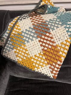 a crocheted blanket sitting on top of a couch