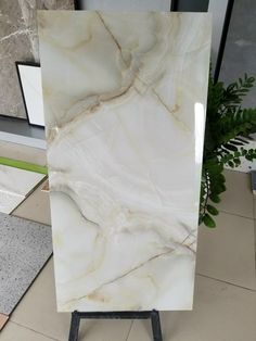 a large white marble slab sitting on top of a wooden stand next to a potted plant