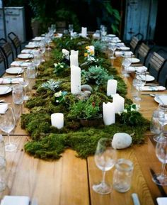 a long table with moss and candles on it