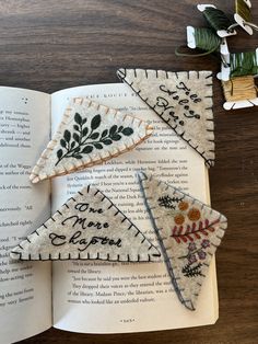 an open book sitting on top of a wooden table next to some scissors and thread