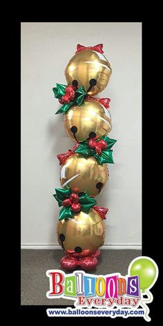 three gold balloons are stacked on top of each other with bows and poinsettis