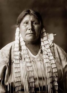 an old black and white photo of a woman with long hair wearing a headdress