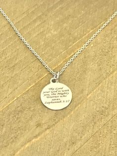 This beautiful necklace is a stainless steel laser engraved pendant with the Zephaniah 3:17 Bible Verse on it to remind the wearer that the Lord is with them. The pendant comes on a stainless steel chain. This pendant is available on your choice of 16, 18, 20, 22, 24, 26, 28 or 30 inch chain. The pendant is also available for individual purchase if you have another chain on which you would like to wear it. This necklace is made of stainless steel to withstand regular wear without tarnishing or c Inspirational Silver Necklace For Father's Day, Inspirational Silver Stainless Steel Jewelry, Meaningful Engraved Stainless Steel Necklace, Inspirational Silver Stainless Steel Necklaces, Inspirational Silver Stainless Steel Necklace, Meaningful Silver Stainless Steel Necklace, Silver Charm Necklace With Laser Engraved Round Pendant, Silver Round Charm Necklace With Laser Engraving, Silver Laser Engraved Charm Necklace