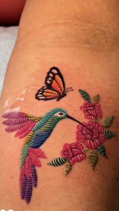 a colorful tattoo with a butterfly and flowers on the side of someone's leg