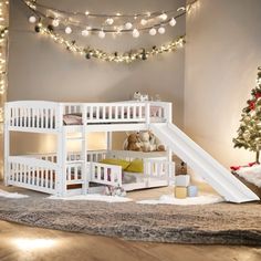 there is a white bunk bed with a slide on the bottom and a christmas tree in the background