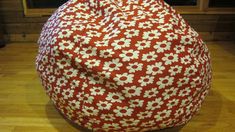 a red and white flowered bean bag sitting on top of a hard wood floor