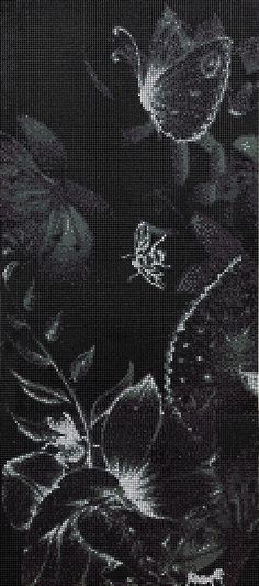 black and white photograph of flowers on a table cloth with an embroidered design in the middle