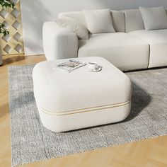 a white couch sitting on top of a wooden floor next to a footstool