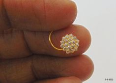 a hand holding a gold ring with small diamonds on the top and bottom, in front of a white background