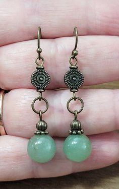 Embrace the allure of nature with these Aventurine Stone Dangle Earrings, beautifully handcrafted to capture the essence of bohemian charm. These exquisite earrings feature genuine jade green aventurine stones, each unique in its rustic, earthy hue, nestled in an elegant bronze setting. Perfect for adding a touch of organic beauty to any outfit, these lightweight, comfortable earrings dangle gracefully, catching the light with every movement. Whether you're dressing up for a special occasion or simply embracing your everyday boho style, these earrings make a thoughtful, handmade gift for nature lovers and free spirits alike. Discover the authentic beauty of bohemian bronze jewelry today!These gorgeous rustic antiqued bronze and aventurine stone boho style earrings with beautiful antiqued b Seed Jewelry Natural, Bronze Dangle Earrings, Charm Earrings Diy, Unique Diy Earrings Ideas, Diy Boho Jewelry, Bohemian Jewelry Diy, Boho Earrings Diy, Winter Jewelry Trends, Whimsical Earrings