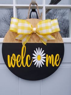 a welcome sign hanging from the side of a garage door with a yellow bow on it