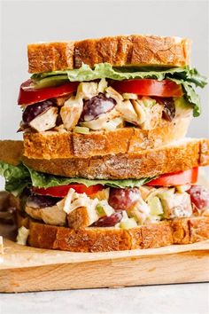 two sandwiches stacked on top of each other with lettuce, tomatoes and chicken