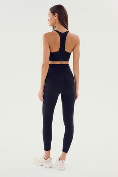 a woman in black sports bra top and leggings looking back at the camera