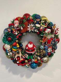 a christmas wreath is hanging on the wall with ornaments all around it and santa's helper