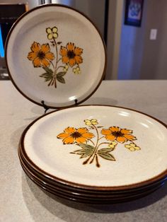 three plates with flowers painted on them sitting on a counter