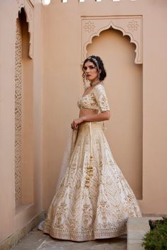 Ivory raw silk lehenga with finest kundan and zardozi embellishments , paired with elbow sleeve embroidered blouse and organza zardozi and pearl work dupatta.From Chamee and Palak's The Romantics collection.DELIVERY TIMEPlease allow 8-12 weeks for your outfit to arrive.FABRIC DETAILSRaw Silk, OrganzaProfessional cleaning only. Elegant Off-white Lehenga For Festive Occasions, Off White Saree Set With Gota Work, Elegant Cream Lehenga For Navratri, Elegant Off White Sharara With Zari Work, Elegant Off-white Sharara With Zari Work, Off White Sharara For Wedding And Navratri, Designer Raw Silk Off-white Dress, Off White Sets With Dupatta For Reception, Festive Cream Cutdana Dress