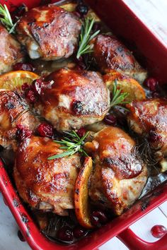 chicken with cranberry sauce and rosemary garnish in a red casserole dish