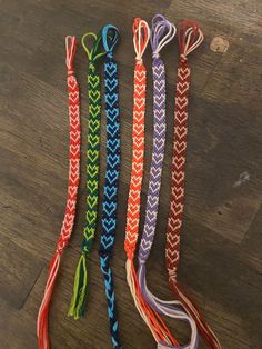 four different colored lanyards on a wooden floor with one tied up and the other untied