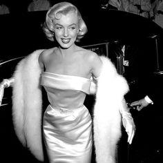 a black and white photo of a woman in a dress with fur stole around her shoulders