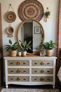 a white dresser topped with lots of potted plants next to a large round mirror