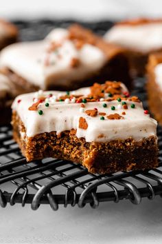 several pieces of cake sitting on a cooling rack with white frosting and sprinkles