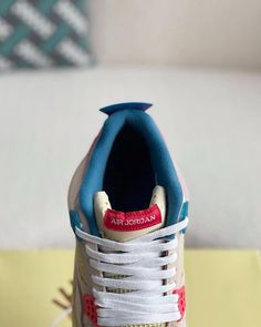 a pair of sneakers with blue and white shoes on top of a yellow table next to a couch