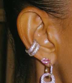 a close up of a person's ear with diamond and pink stones on it