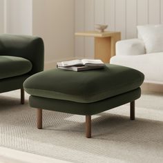 a green ottoman sitting on top of a rug next to a white couch