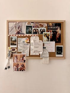 a bulletin board with pictures and notes attached to the back of it, hanging on a wall