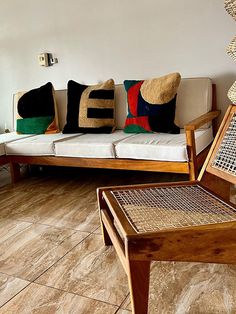 a living room filled with furniture and pillows on top of wooden flooring next to a white wall