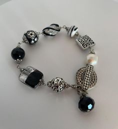 This hand made bracelet is ONE OF A KIND.  You will receive the actual bracelet in the picture. I would describe this bracelet as vintish- that is my word for a beautiful blend of vintage beads and modern pieces. You will find a large vintage two tone foil bead, a vintage lamp work black and clear bead, a faceted crystal, bali silver beads, and a 13mm freshwater pearl.  The pearl is baroque which means it has a personality of it's own. It is off round and it has indentions and unique characteris Handmade Adjustable Baroque Pearl Beaded Bracelets, Classic Baroque Pearl Bracelets, Luxury Elegant Baroque Pearl Beaded Bracelets, Luxury Baroque Pearl Bracelet With Pearl Charm, Luxury Baroque Pearl Charm Bracelets, Chunky Charm Bracelet, Bali Silver, Hammered Metal, Crystal Charm