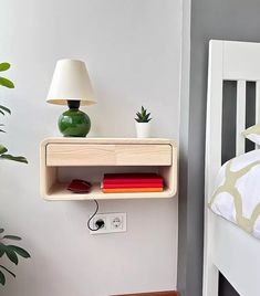 a white bed with a wooden shelf and lamp