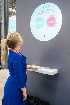 a woman standing in front of a wall with a display on it's side