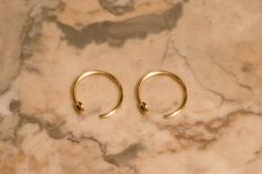 two pairs of gold hoop earrings on a marble surface