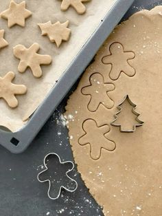 gingerbread cookies and cookie cutters sitting on a table next to an uncooked cookie sheet