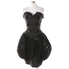 A Vintage 1980s Victor Costa Black Textured Fabric And Black Lace Corset Dress. This Stunner Is Designed With A Lace Accented Sweetheart Neckline And Back, A Row Of Four Sateen Bows To The Front, And A Fitted Skirt Featuring Ruffle Edged Lace Bustle Accents To The Sides. There Is A Hidden Zipper To The Back And A Brand Label Sewn To The Black Lining. Retains Original Retail Tag. - 30" Bust, 24" Waist, 32" Hip, 29" Length Including Lace. Black Fitted Corset Dress With Ruffles, Black Overbust Corset Dress For Formal Occasions, Black Overbust Mini Dress For Cocktail, Black Overbust Cocktail Dress, Black Cocktail Dress With Overbust Shape, Black Overbust Mini Dress For Costume Party, Vintage Black Dress For Costume Party, Black Fitted Mini Dress With Overbust, Black Overbust Mini Dress For Evening