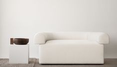 a white couch sitting on top of a carpeted floor next to a vase filled with flowers