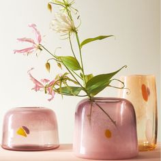 three vases with flowers in them sitting on a table next to eachother