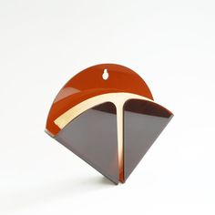 an orange and brown brooch sitting on top of a white table