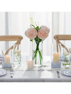 the table is set with candles and flowers in glass vases on top of it