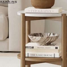 a stack of books sitting on top of a wooden table next to a white couch