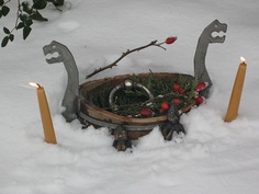 a basket filled with candles and ornaments in the snow next to some plants on top of it