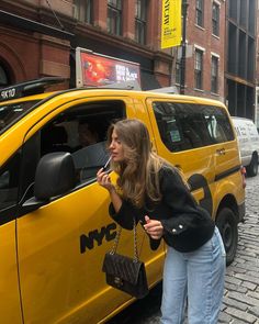 a woman standing next to a yellow taxi