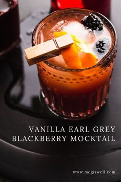 a close up of a drink in a glass on a table with the words vanilla ear grey blackberry cocktail