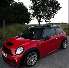 a small red car parked in front of a tree