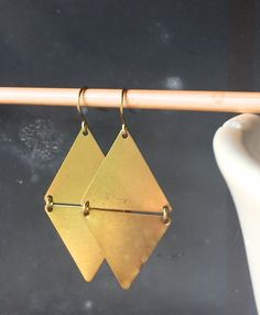 Simple, geometric, and bold.  These earrings feature simple brass triangles, linked together to form a cool golden diamond.  Perfect to elevate every outfit.  Earrings measures about 2.25" long.  These earrings are so fashion-forward, and so beautiful, too.  Earrings measure 2.25" long. Adjustable Geometric Minimalist Earrings, Adjustable Minimalist Geometric Earrings, Geometric Metal Earrings For Everyday, Modern Gold Diamond-shaped Earrings, Triangle Gold Metal Earrings, Gold Triangle Metal Earrings, Gold Triangle Minimalist Earrings, Minimalist Gold Triangle Earrings, Adjustable Gold Triangle Earrings