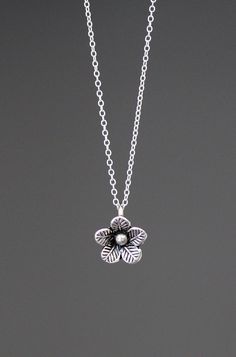 A lovely three dimensional Bali Silver flower charm simply dangles from a silver chain.  Choose from a 1mm silver chain with a silver spring ring clasp, or a 1.5mm silver chain with a silver lobster clasp. Each chain measures 16" with an extension to 18".  Please send a message if a different length chain is desired. Great as a layering piece or wonderful by itself.  Multiple quantities may be ordered.  Bali Silver flower: 10x12mm Total length of charm: 1/2" Silver chain: 1mm or 1.5mm All silver Sterling Silver Charm Necklace With Flower Charm, Dainty Silver Charm Necklace With Flower Pendant, Delicate Silver Charm Necklace With Flower, Sterling Silver Flower Charm Necklaces, Silver Delicate Flower Charm Necklace, Delicate Silver Flower Charm Necklace, Delicate Silver Flower-shaped Charm Necklace, Delicate Silver Flower Shape Charm Necklace, Dainty Silver Flower Charm Necklace