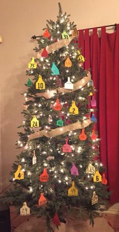 a decorated christmas tree in front of a red curtain with numbers on the top and bottom