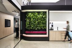 a living wall in an office with people walking by